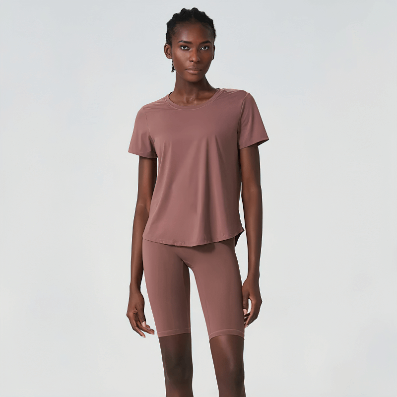 Woman wearing two-piece yoga set in solid color, featuring short sleeves and breathable Lycra, perfect for gym and yoga sessions.